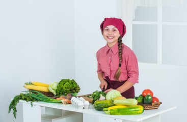 Committed to good food. kid wear chef uniform. child in hat and apron. cook with vegetables