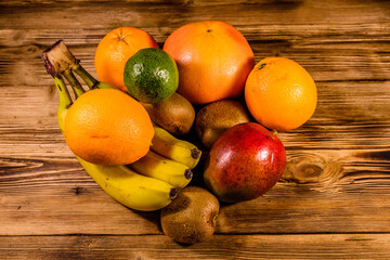 Wall Mural - Still life with exotic fruits. Bananas, mango, oranges, avocado, grapefruit and kiwi fruits on wooden table