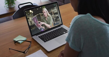 Poster - African american woman having a video call with female office colleague on laptop at home