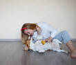 © Aleksandra Iarosh - a young woman combing a beagle dog with a furminator. grooming at home