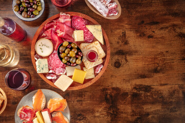 Wall Mural - Charcuterie and cheese platter with wine, top shot on a rustic background with copy space. Italian antipasti or Spanish tapas, shot from above with olives and salmon sanwiches