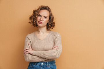 Displeased ginger woman frowning while posing with arms crossed