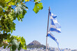 flag of greece ripped by storming wind on landscape of athens