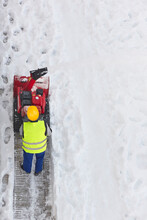 Worker Cleaning Snow On The Sidewalk With A Snowblower. Wintertime