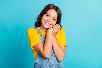 Poster - Photo of sweet adorable small school girl wear denim jeans overall arms together cheek smiling isolated blue color background