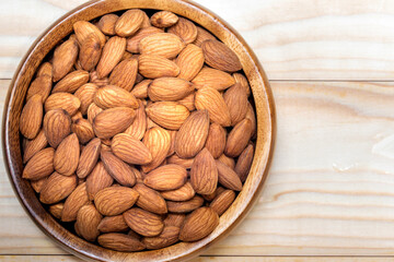 Peeled almond in a wooden bowl on wooden plank.