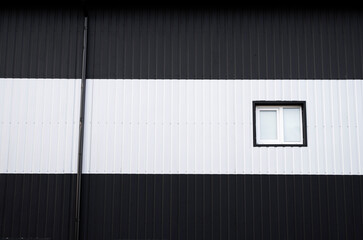 Wall Mural - Black and white corrugated iron sheet used as a facade of a warehouse or factory with a windows. Texture of a seamless corrugated zinc sheet metal aluminum facade. Architecture. Metal texture.