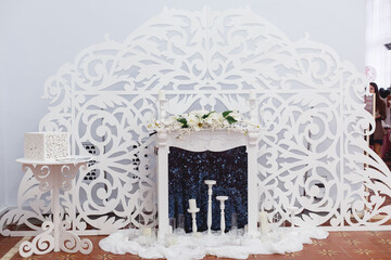 Wall Mural - Elegant white fireplace on beautiful white toreutic background. Elegant wedding ceremony