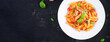 Classic italian pasta penne alla arrabiata with basil and freshly grated parmesan cheese on dark table. Penne pasta with chili sauce arrabbiata. Top view, above, banner