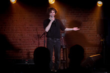 Young Caucasian Male Comedian Performing His Stand-up Monologue On A Stage Of A Small Venue