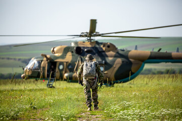 Military helicopter with soldiers. Armed conflict between Israel and Palestine, military action. A soldier in camouflage clothing goes to a military helicopter. Air armament, parachutist.