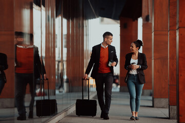 Business man and business woman talking and holding luggage traveling on a business trip, carrying fresh coffee in their hands.Business concept