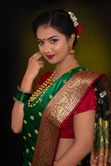 Indian model wearing traditional Maharashtrian bridal green sari and jewelry. Looking at Camera.