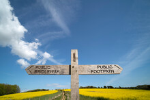 Public Footpath And Public Bridalway Sign On A Wooden Post In The Countryside With A Blue Sky.