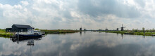 Panorama View Of The Windmills And Canals Of Kinderdijk In South Holland With A Dock And Boat In The Foreground