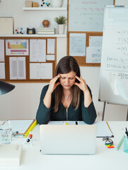 Wall Mural - Young tired female online professor having headache.
Tired woman sitting in her home office during class break and holding her head with hands.