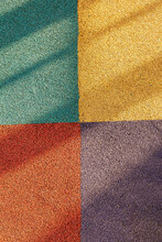Junction Of Four Multi-colored Squares Of Floor Covering With Long Shadows. Padded Floor Covering With Rubber Granules. Special Rubber Coating For The Playground Or Sports Activity.
