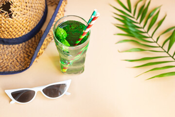 Wall Mural - green lemonade tarragon or basil beverage summer background refreshing ice drink straw hat, sunglasses relax positive mood vacation top view