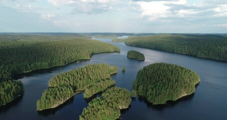 Wall Mural - Aerial view of small islands on a blue lake at sunset. Birds eye view of scenic lake surrounded by green forest. Drone 4k footage.
