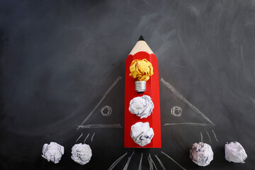 Education concept image. Creative idea and innovation. Crumpled paper as light bulb metaphor and rocket from pencil over blackboard