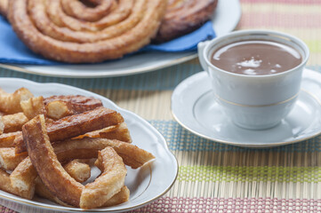 Canvas Print - Vertical shot of churros beside a cup of hot chocolate at home on a white plate