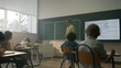© stockbusters - Students sitting at desks in classroom. Teacher explaining lesson to pupils