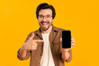 © Valerii Apetroaiei - Young bearded man in glasses shows on blank smartphone screen isolated on orange background.