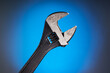 © Igor Nikushin - Adjustable wrench with black handle on a blue background