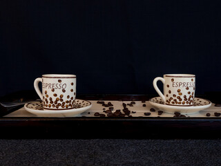 Poster - Closeup shot of coffee cups surrounded by coffee beans on a tray