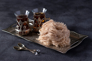 Tea ceremony with Turkish cotton candy Pismaniye on vintage tray on dark gray background.