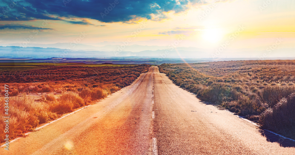 Carretera a través del desierto. Asfalto y viaje en coche con puesta de sol idílico . Concepto de viaje por carretera  y aventuras. - obrazy, fototapety, plakaty 