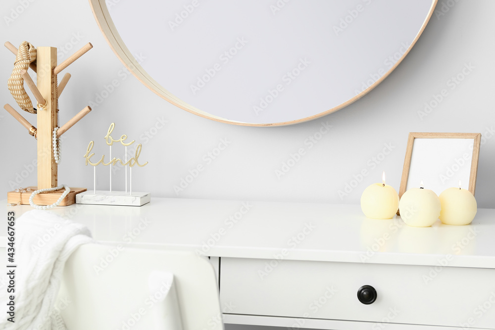 Decor and candles on table near light wall