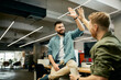 © Drazen - Happy creative business colleagues giving high-five to each other while working in the office.