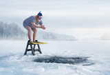 Fototapeta  - Fuunny overweight, retro swimmer about to jump into ice hole in the lake, with copy space