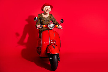 Sticker - Full body photo of excited aged woman happy positive smile ride scooter trip isolated over red color background