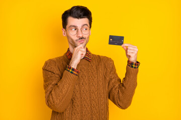 Canvas Print - Photo of minded thoughtful man look hold plastic credit card hand chin isolated on yellow color background