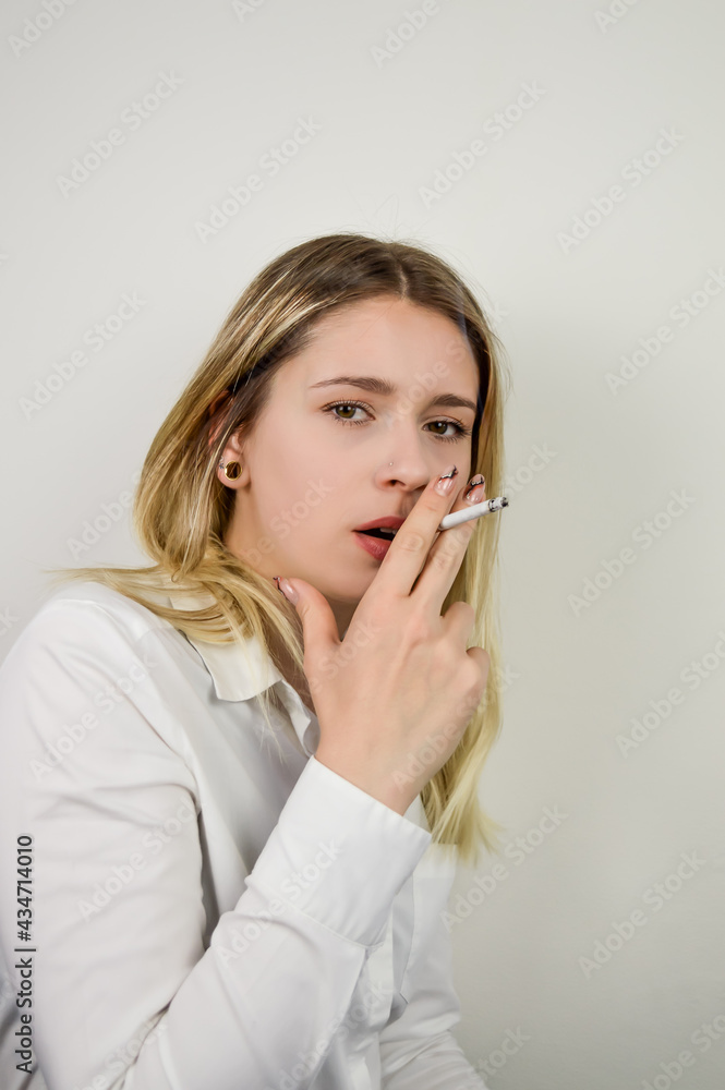 Portrait of a beautiful young blonde woman who is smoking a cigarette ...