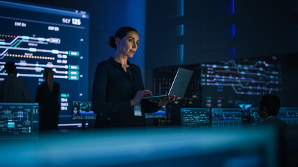 Aufkleber - Beautiful Confident Female Project Manager works on Laptop Standing in Telecommunications System Control Room. In Background Big Screen Showing Infographics of Infrastructure, Charts, System Analysis