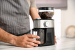 © New Africa - Man using electric coffee grinder in kitchen, closeup