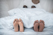 © zinkevych - Husband and wife feet peeking out from under blanket