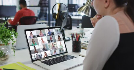 Canvas Print - Caucasian woman having a video conference with office colleagues on laptop at office