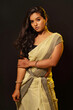 Young Indian fashion model in Saree on black background. Looking at camera. Serious look. Unhappy and sad.