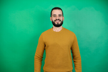 Wall Mural - Handsome man wearing casual clothes over isolated green background with a happy face standing and smiling with a confident smile showing teeth