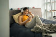 © Yakobchuk Olena - Woman wearing headphones laying at bed, listening music and looking at her smartphone