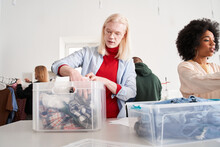 Woman And Man Putting Clothes Into The Plastic Container While Sorting