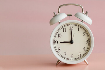 white table clock on yellow and pink background time