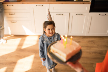 Wall Mural - Girl looking at her birthday cake while preparing to blowing out the candles