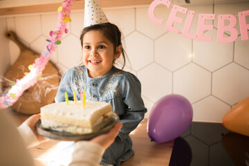 Wall Mural - Girl looking at her mother after blowing candles at her birthday cake