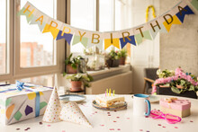 Birthday Party Table With Birthday Cake With Candles, Balloons And Colored Decor