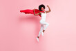 Full length body size view of cheery girl jumping wearing hero costume showing strong biceps muscles isolated on pink pastel color background